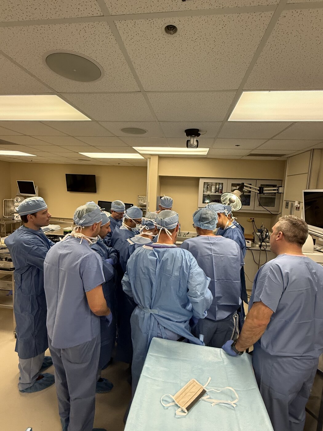 Surgeons in scrubs gathered around a station during a hands-on surgical skills lab